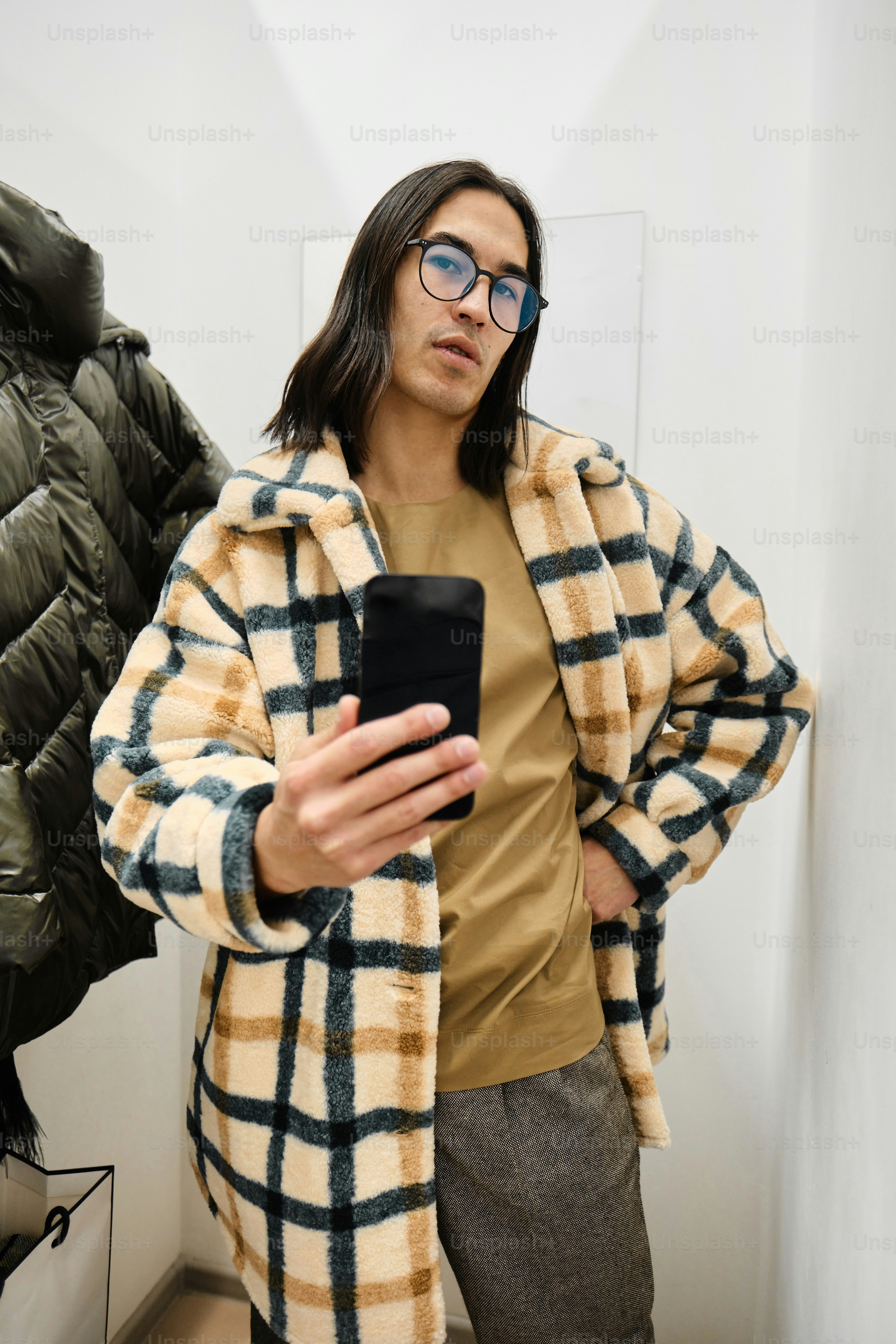 man in a fitting room taking pictures of clothes