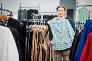 uma mulher em pé em frente a um rack de roupas