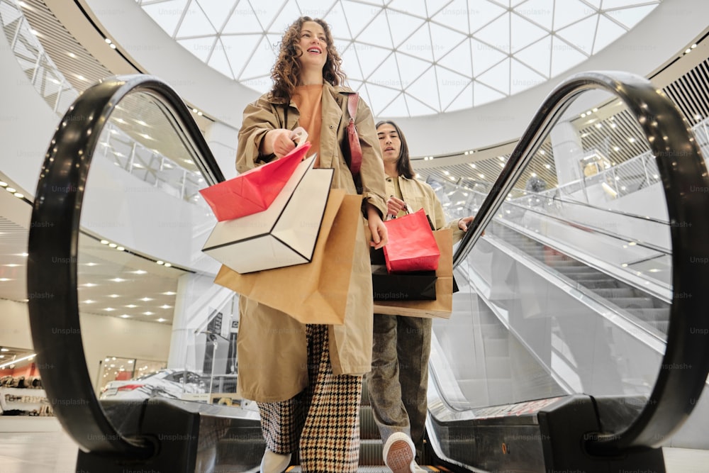 two women walking down an escalator carrying shopping bags