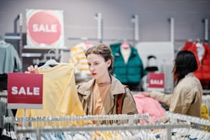 a woman looking at a sale sign in a clothing store