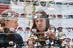 two women looking at sunglasses in a store window