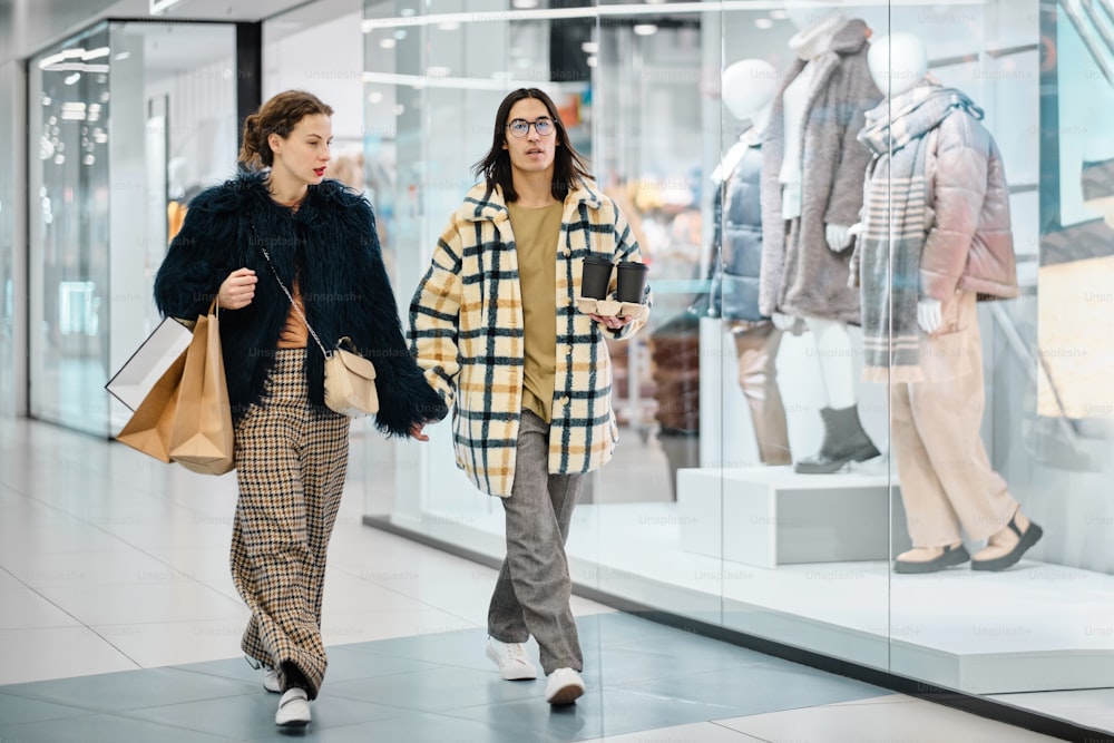 two women walking down a mall carrying shopping bags