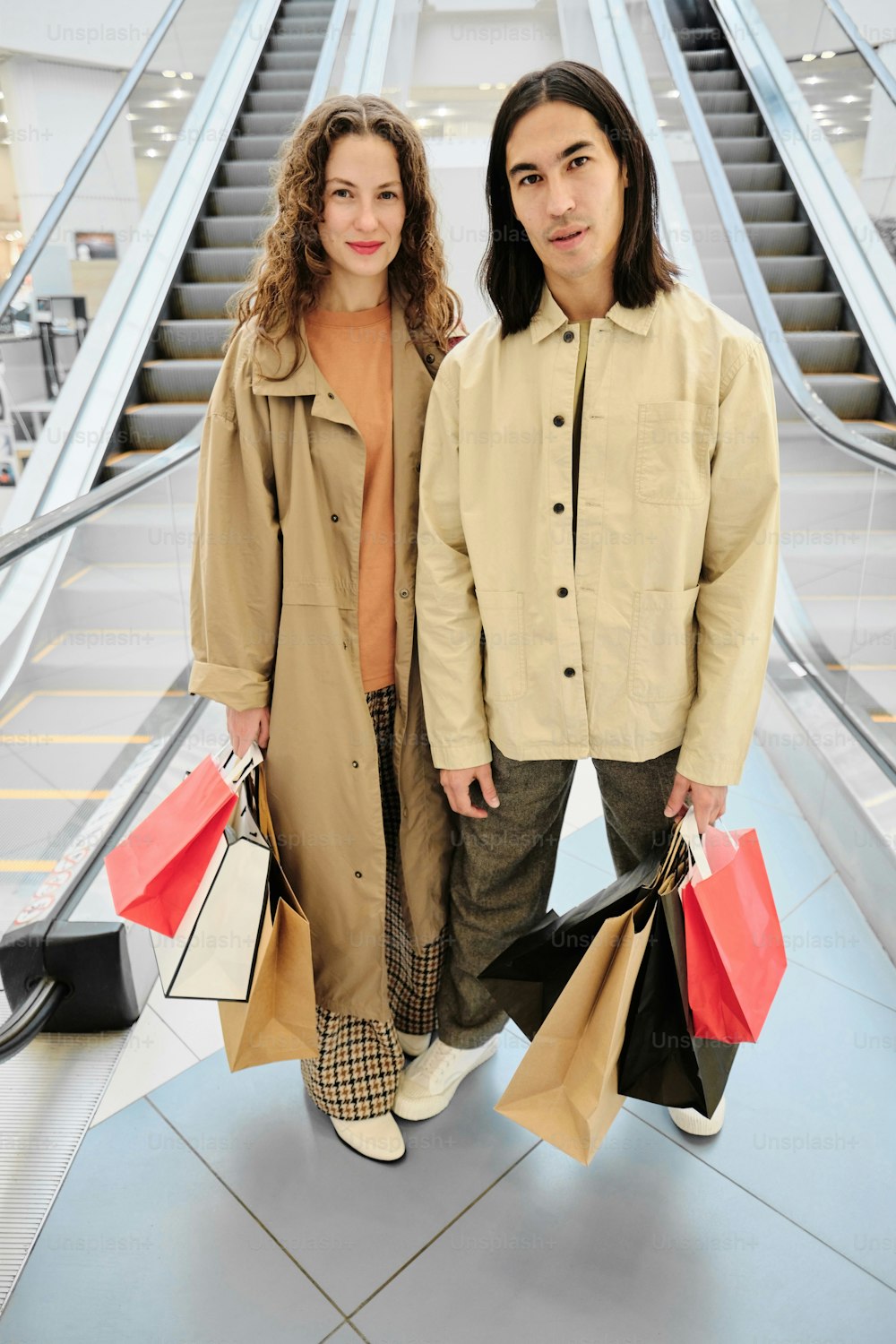 a man and a woman standing next to each other holding shopping bags