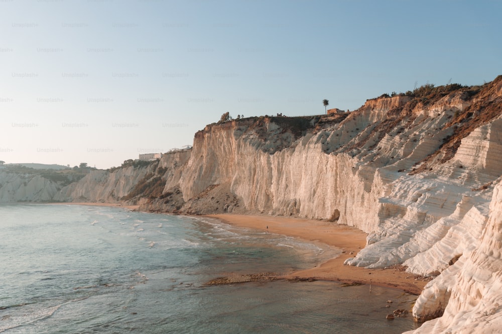 a beach with a cliff and a body of water