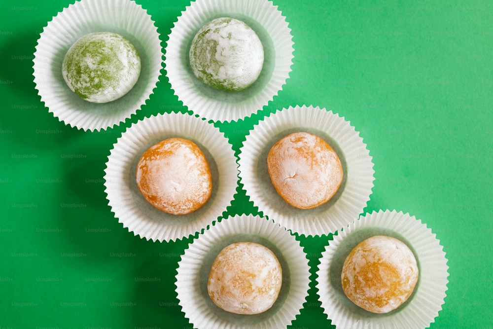 a group of four powdered donuts sitting on top of a green table