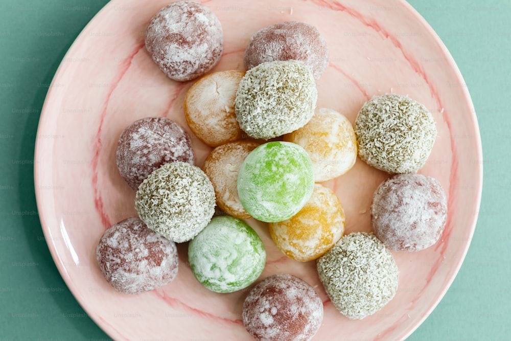 a pink plate topped with powdered donuts on top of a green table