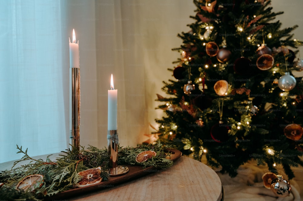 a lit candle on a table next to a christmas tree