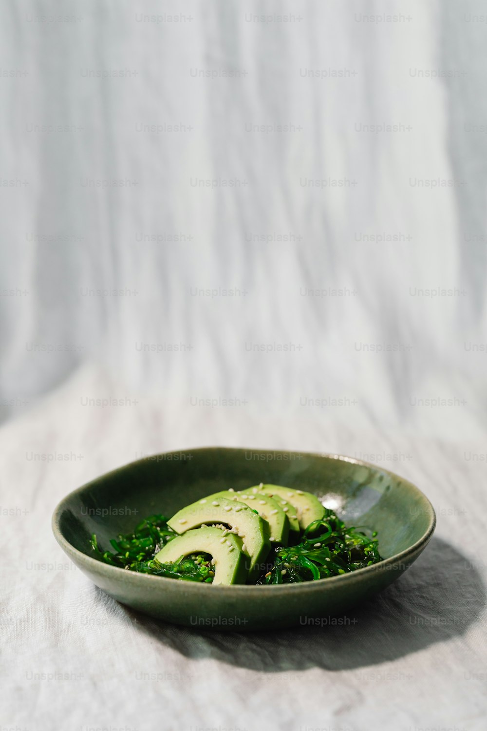 a green bowl filled with sliced avocados on top of a table
