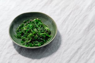 a bowl filled with green vegetables on top of a table