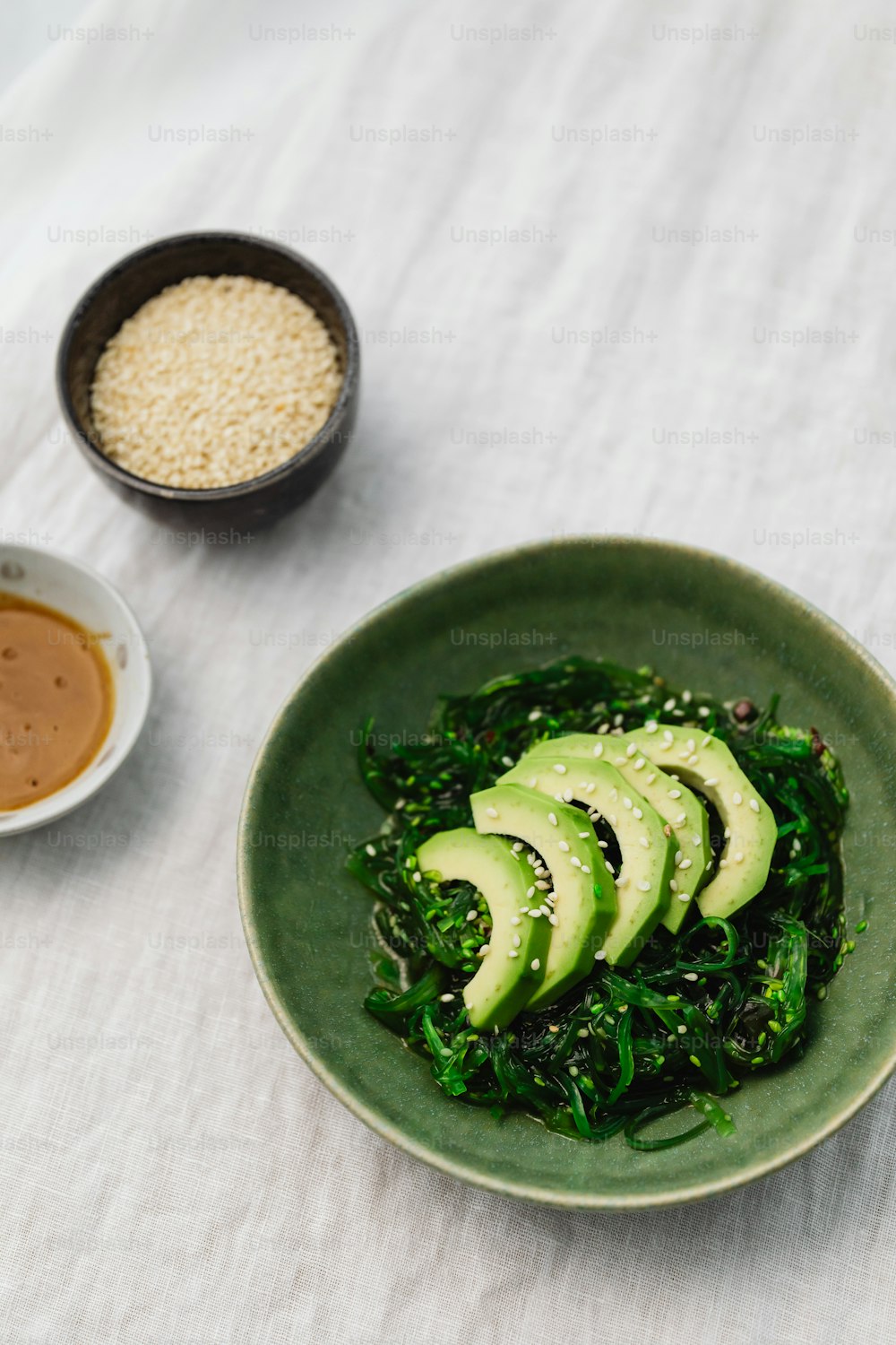 a green plate with sliced avocados and sesame seeds