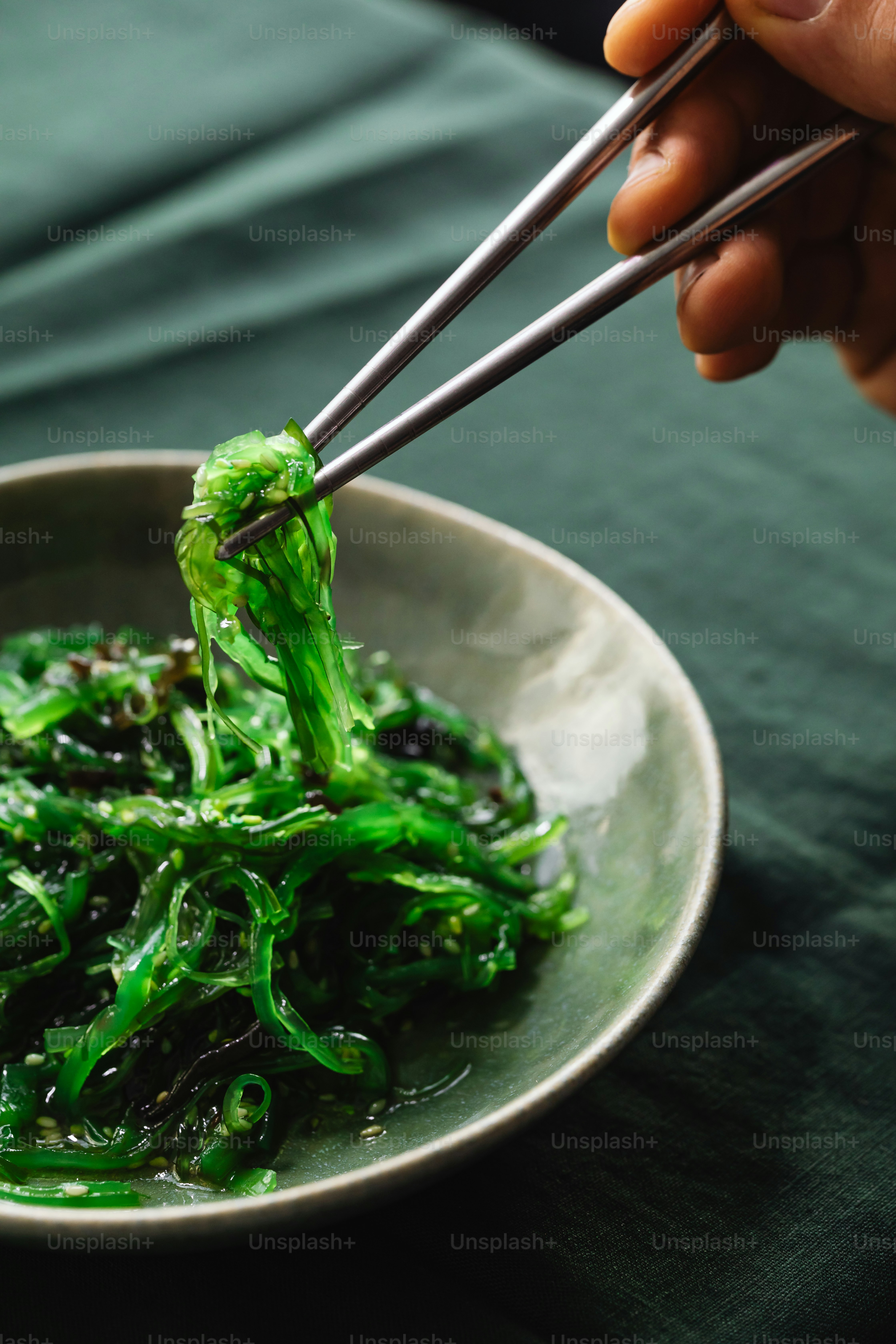una persona sosteniendo palillos sobre un plato de comida