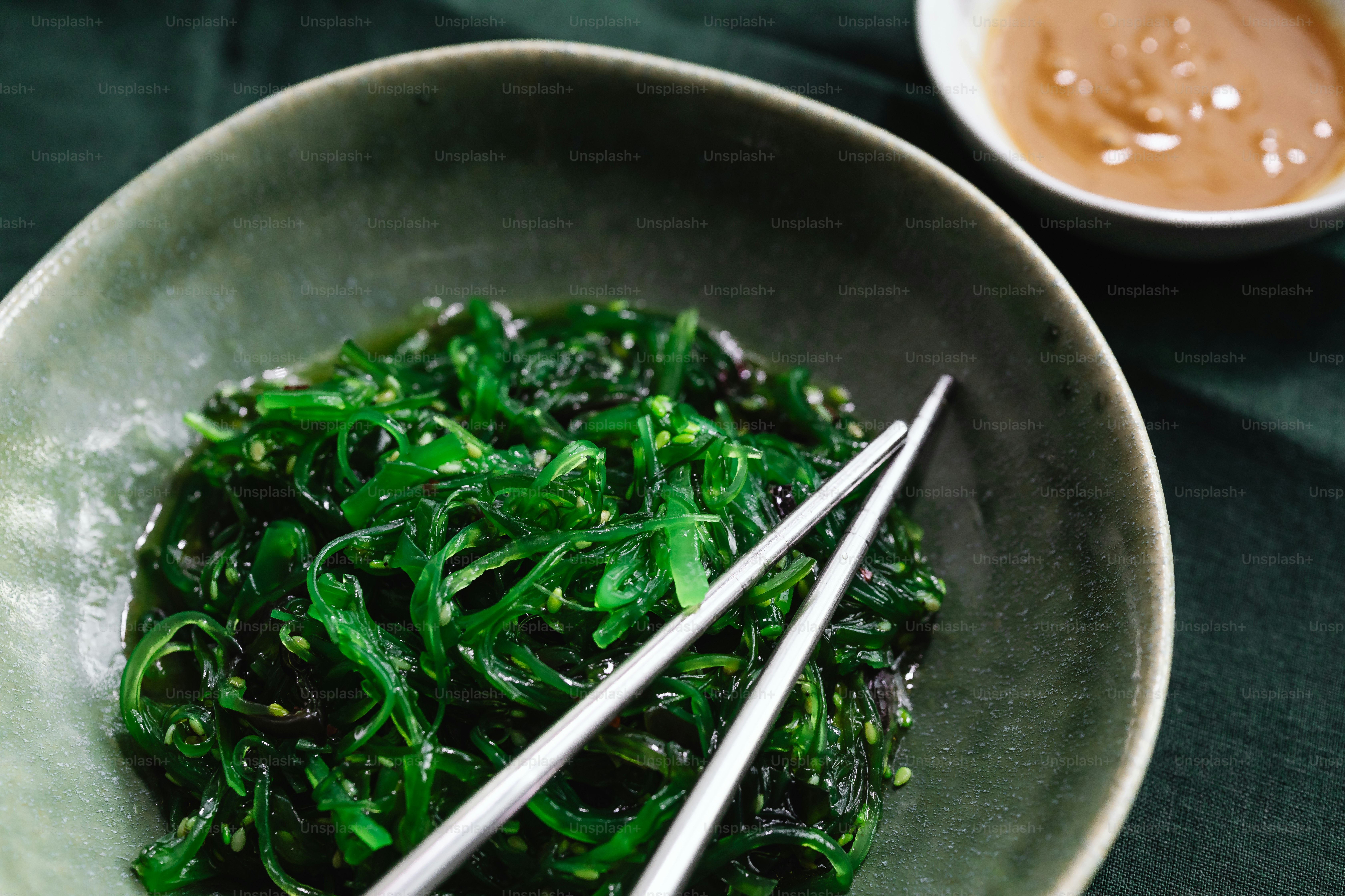 a bowl of green vegetables with chopsticks in it