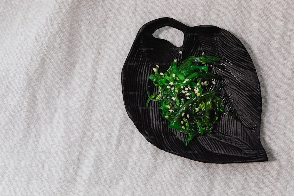 eine schwarze Tüte mit einem Strauß grüner Blätter drauf
