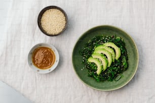a green plate with sliced avocado and sesame seeds