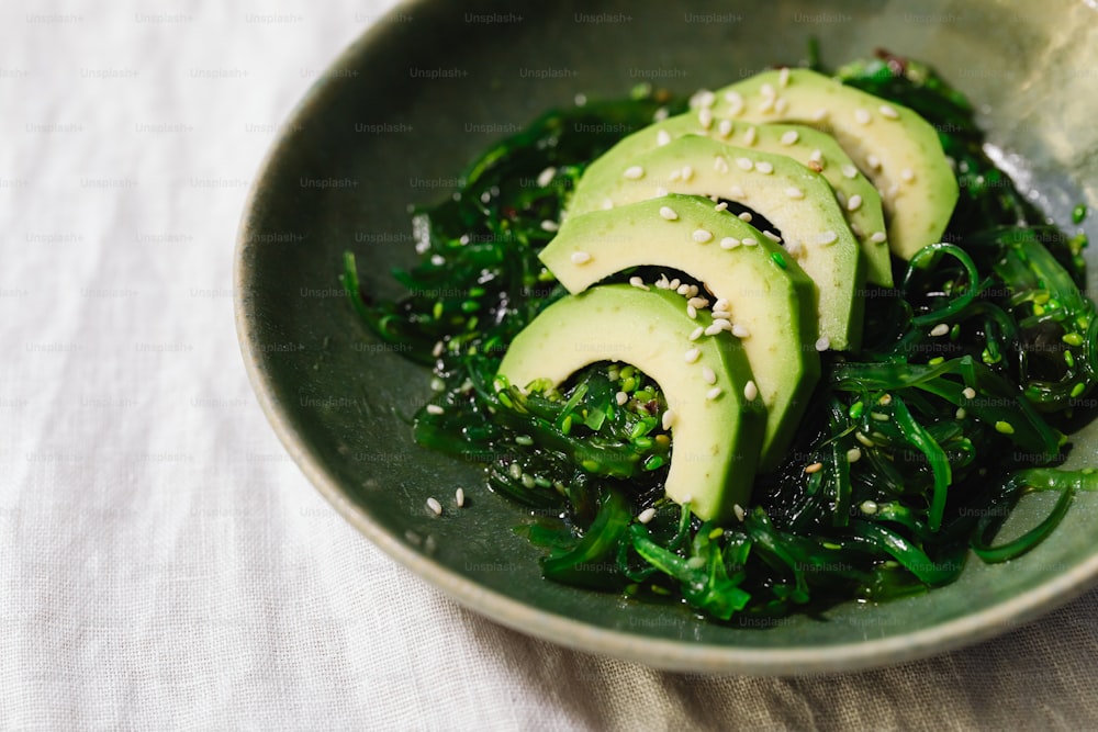 a bowl filled with sliced avocados and greens