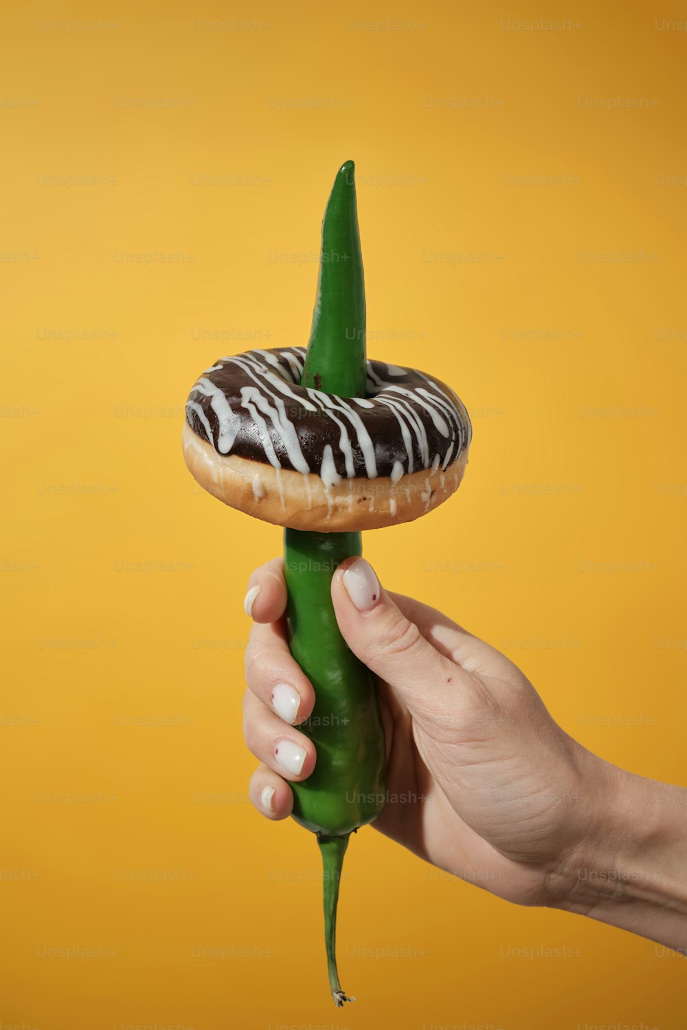 a hand holding a donut with a sprig of icing