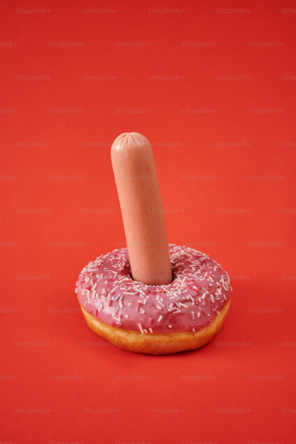 ein Donut mit einer einzelnen rosa Glasur und Streuseln darauf