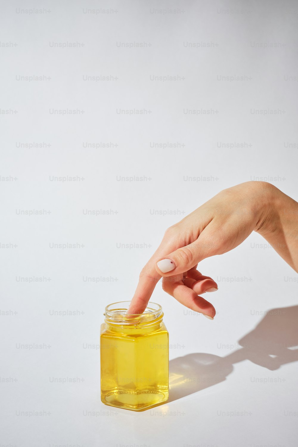 a woman's hand reaching for a jar of honey