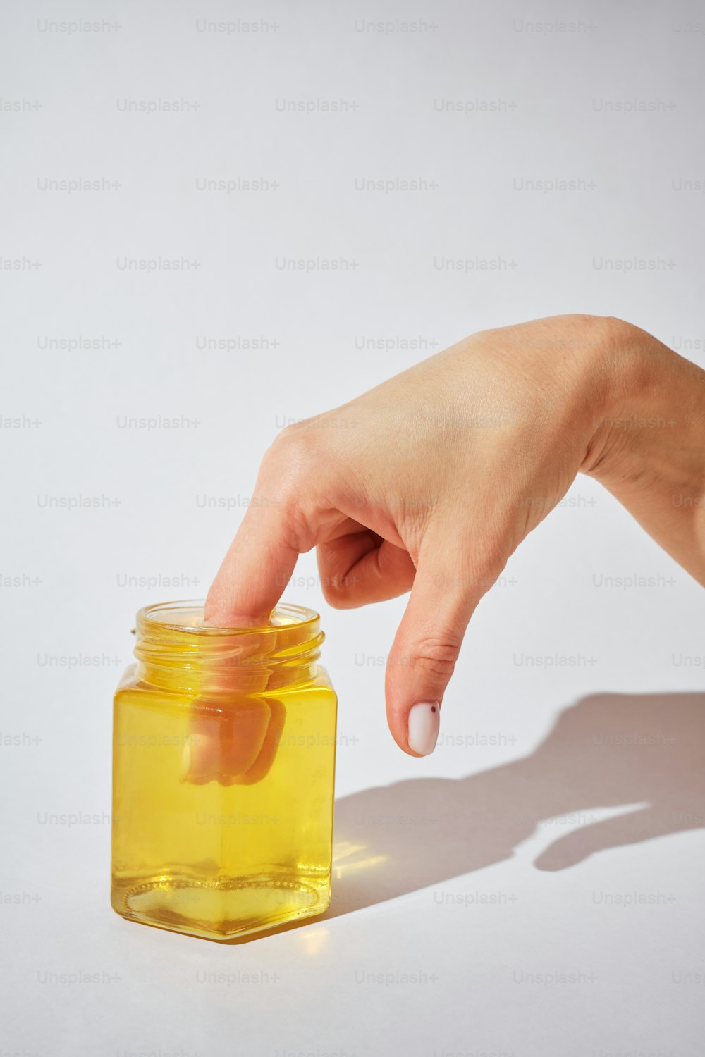 a person's hand reaching for a jar of honey