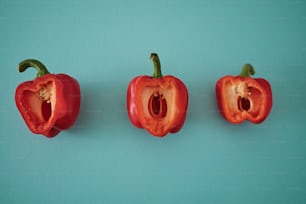 three red peppers on a blue background