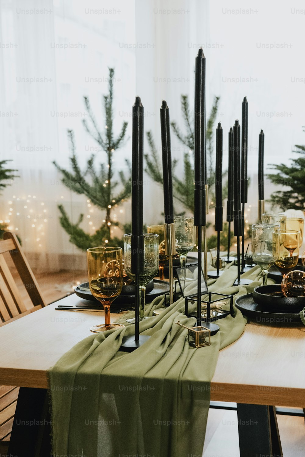 a wooden table topped with black plates and candles