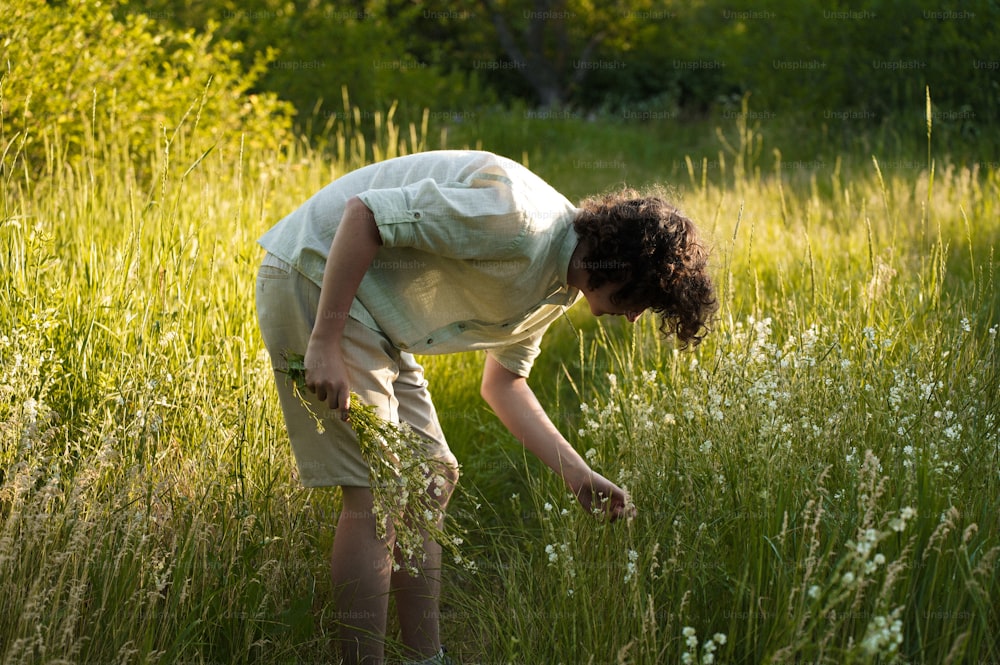 a woman bending over in a field of tall grass
