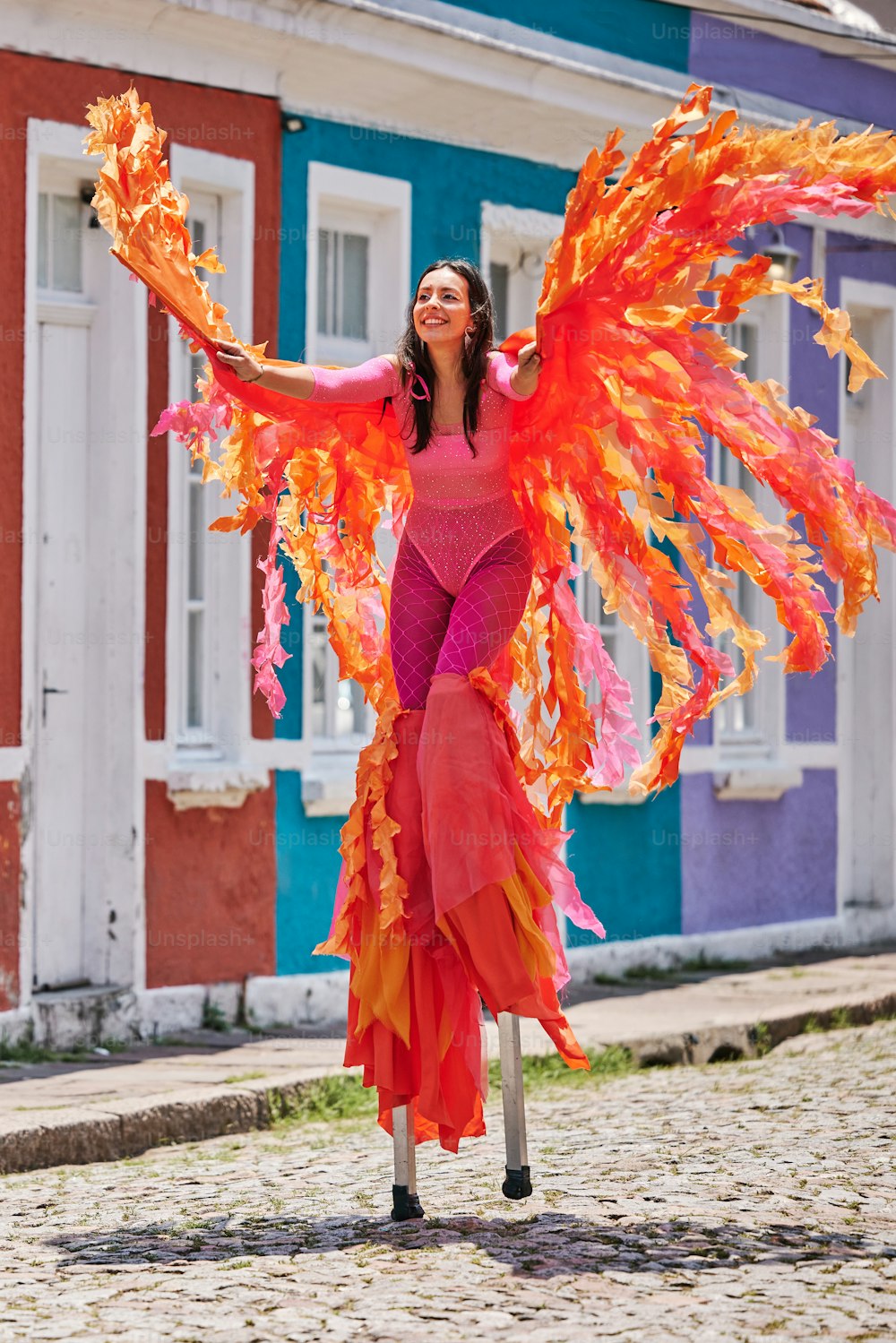 uma mulher em um top rosa e asas laranja e amarela