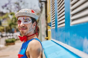 a man with face paint on sitting on a bench
