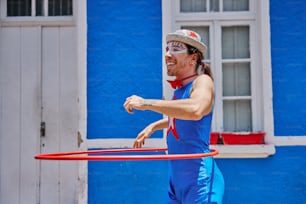 a man in blue jumpsuit playing with a red hula hoop
