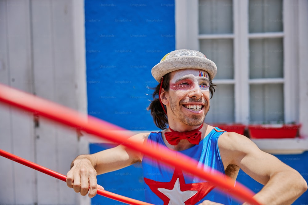 a man with a painted face and a red ribbon around his neck