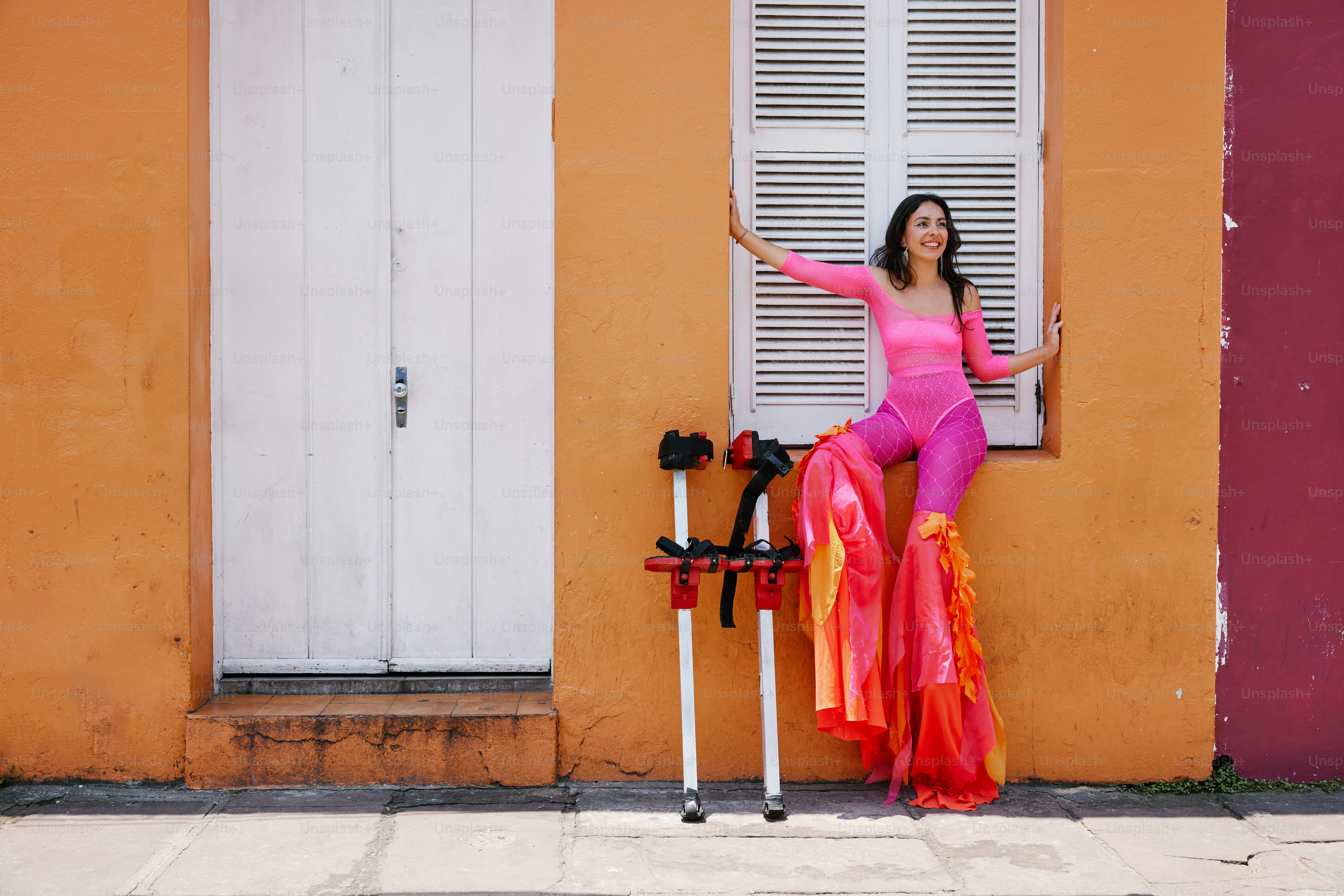 a woman in a pink outfit leaning against a wall