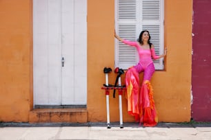 a woman in a pink outfit leaning against a wall