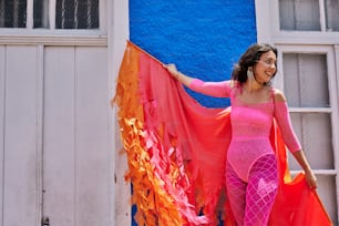 a woman in a pink outfit holding a red and orange kite