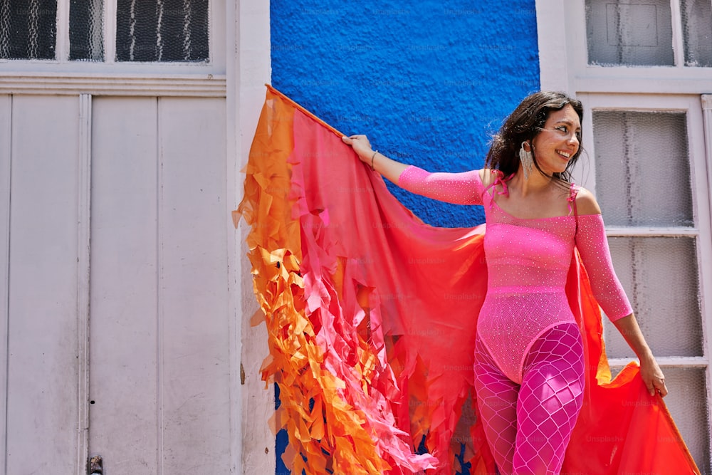 a woman in a pink outfit holding a red and orange kite