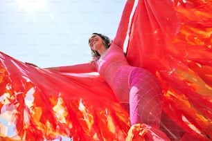 a woman in a pink outfit holding a red scarf