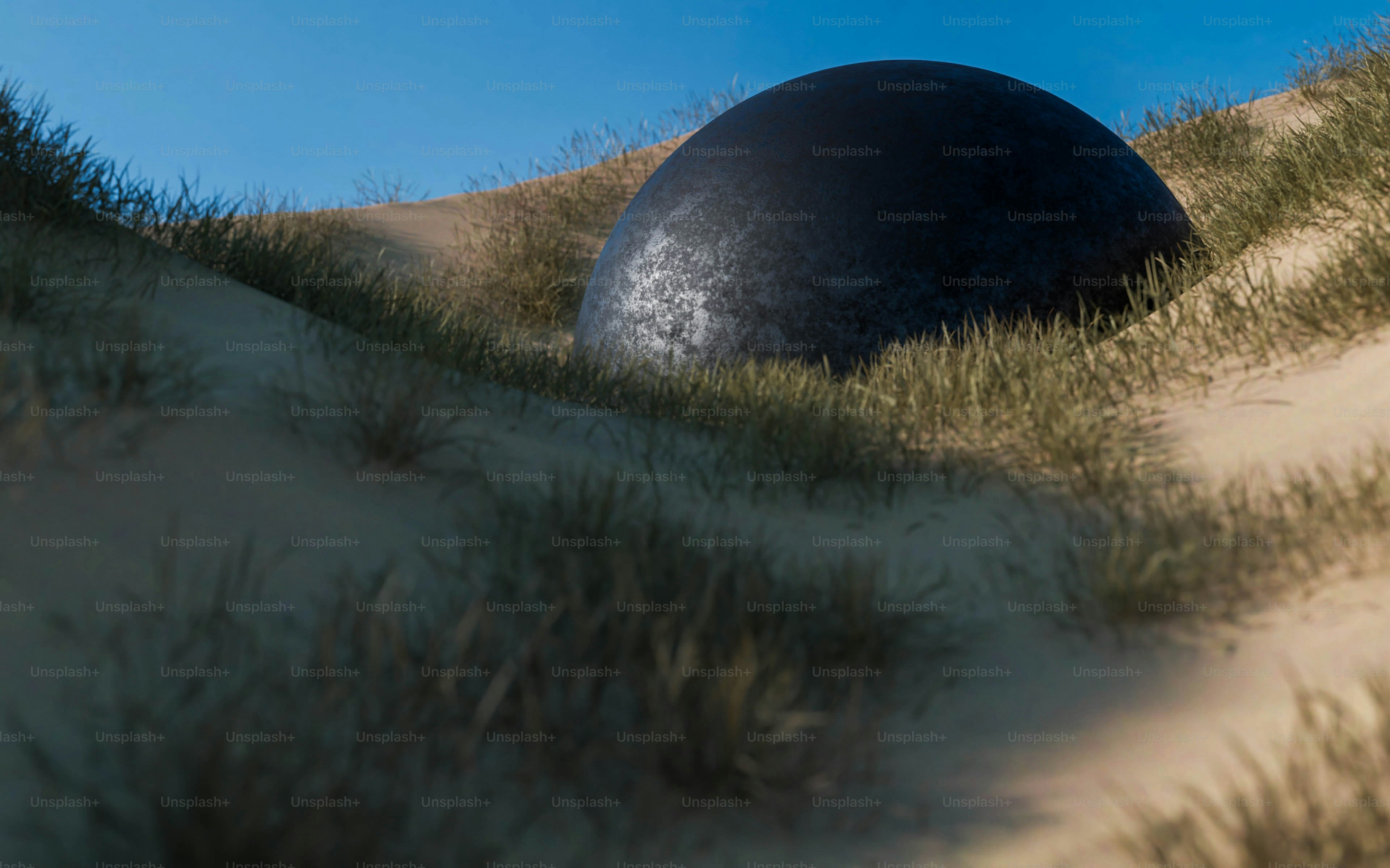 a large black rock sitting in the middle of a grass covered field