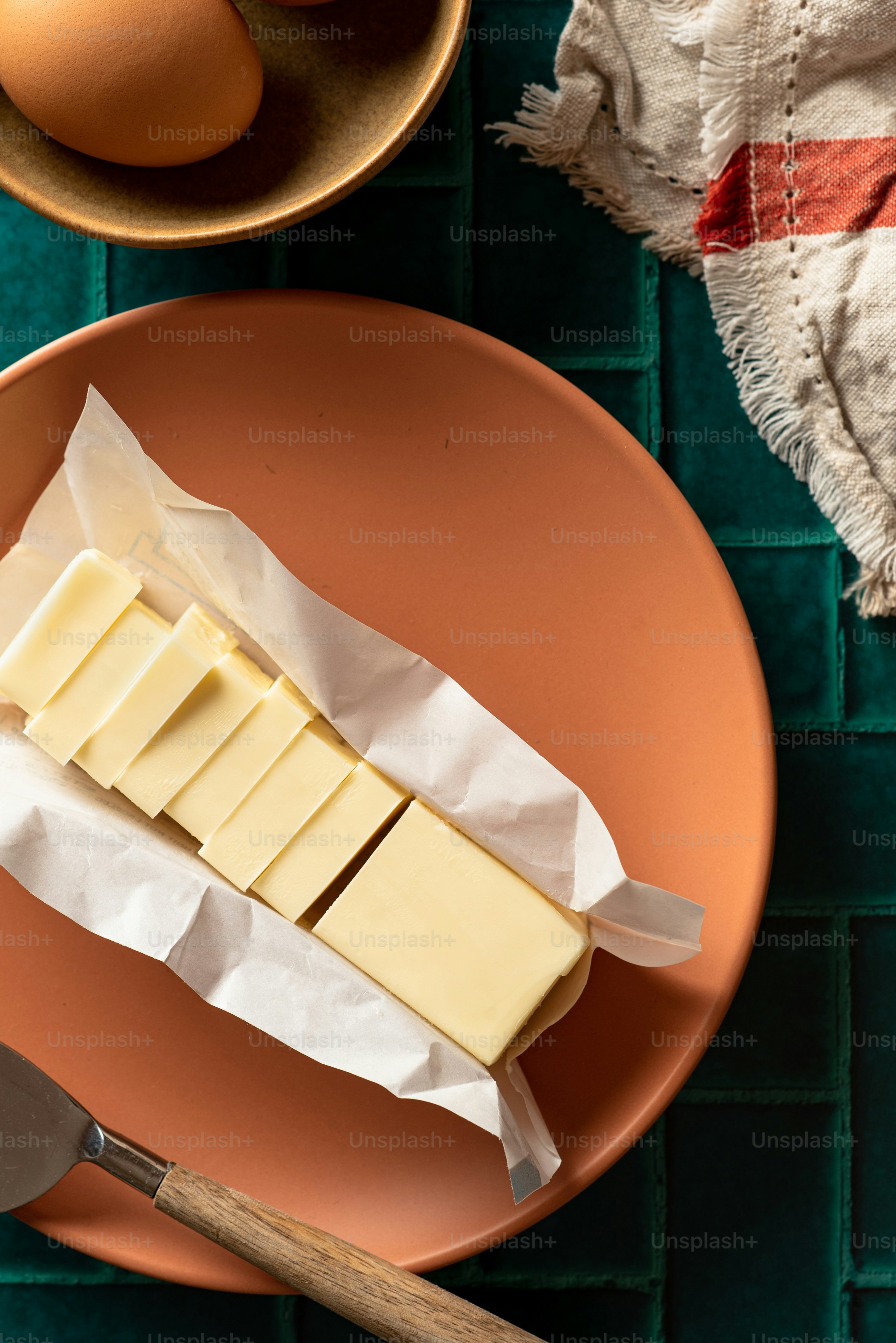 a piece of butter on a plate next to a bowl of eggs