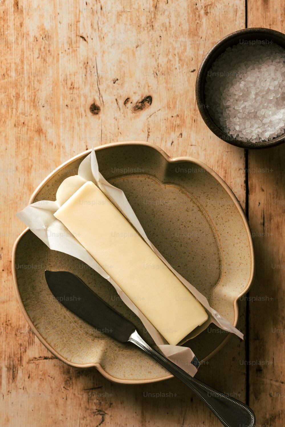 a plate with a piece of cheese on it next to a bowl with a spoon