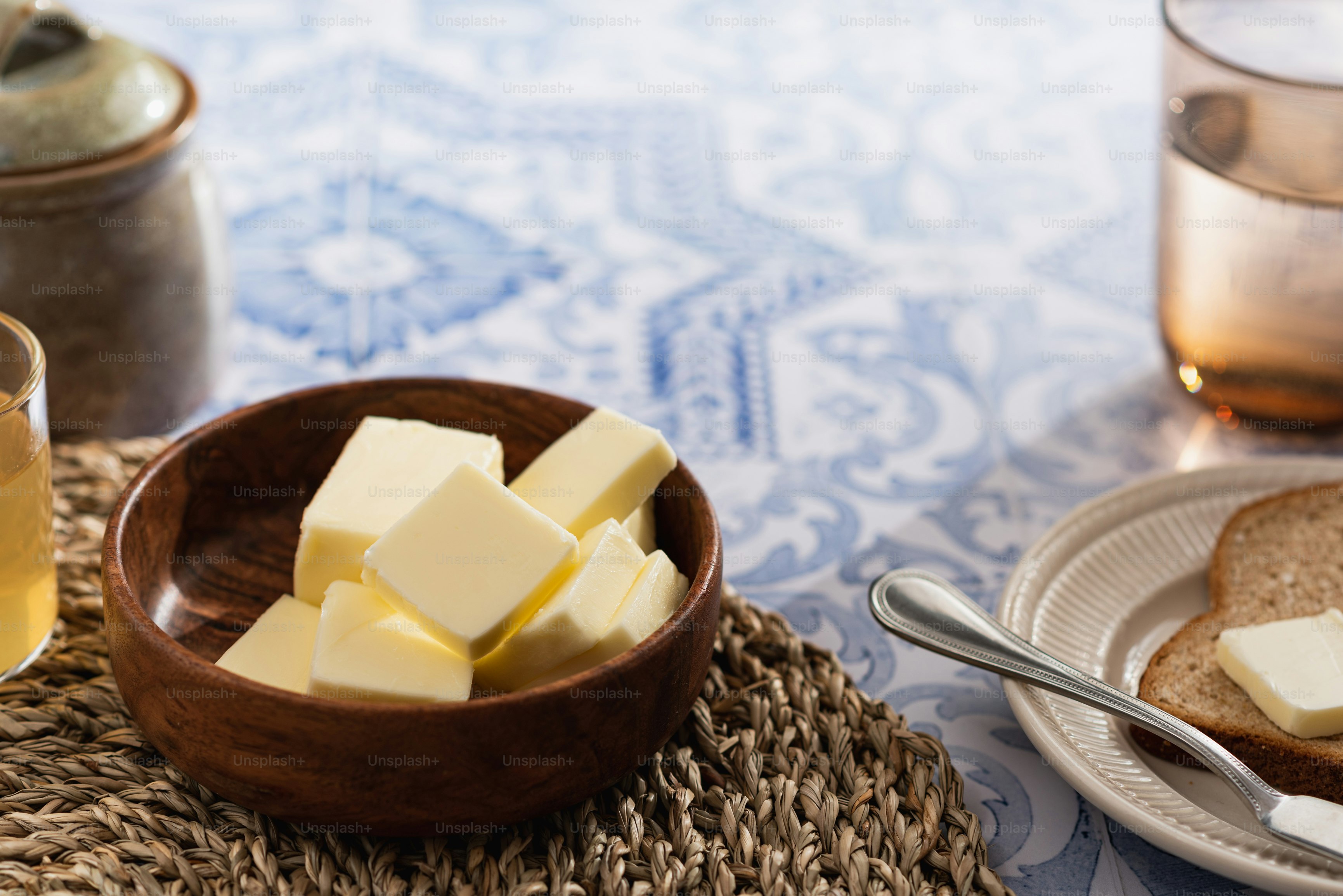 a bowl of butter next to a bowl of bread and a glass of water
