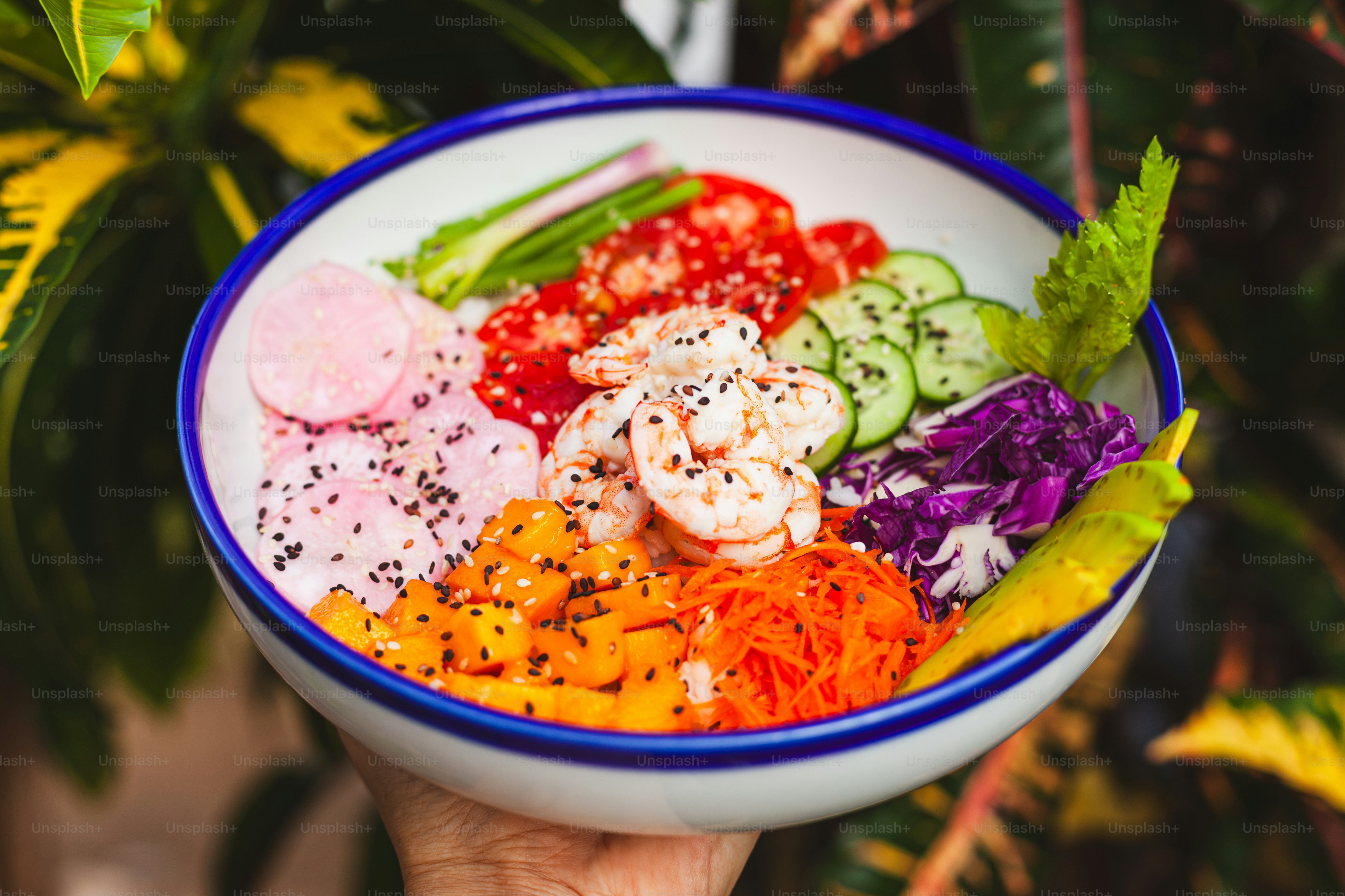 a person holding a bowl filled with different types of vegetables