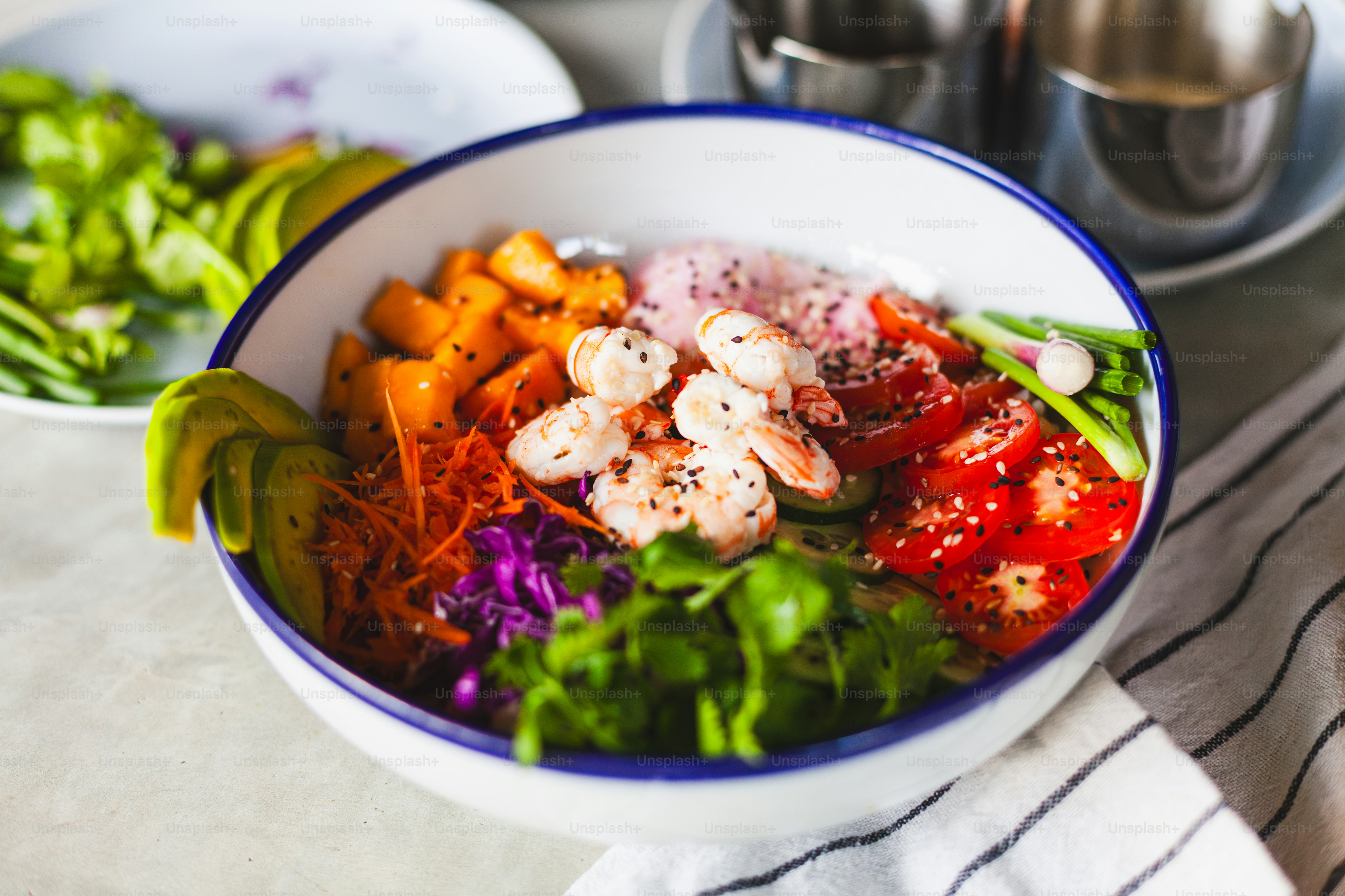 a bowl of food with shrimp, carrots, lettuce, and other