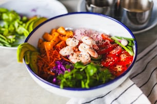 a bowl of food with shrimp, carrots, lettuce, and other