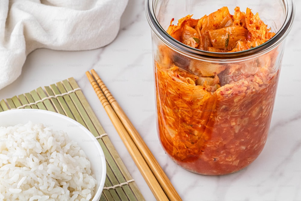 a glass jar filled with rice next to chopsticks