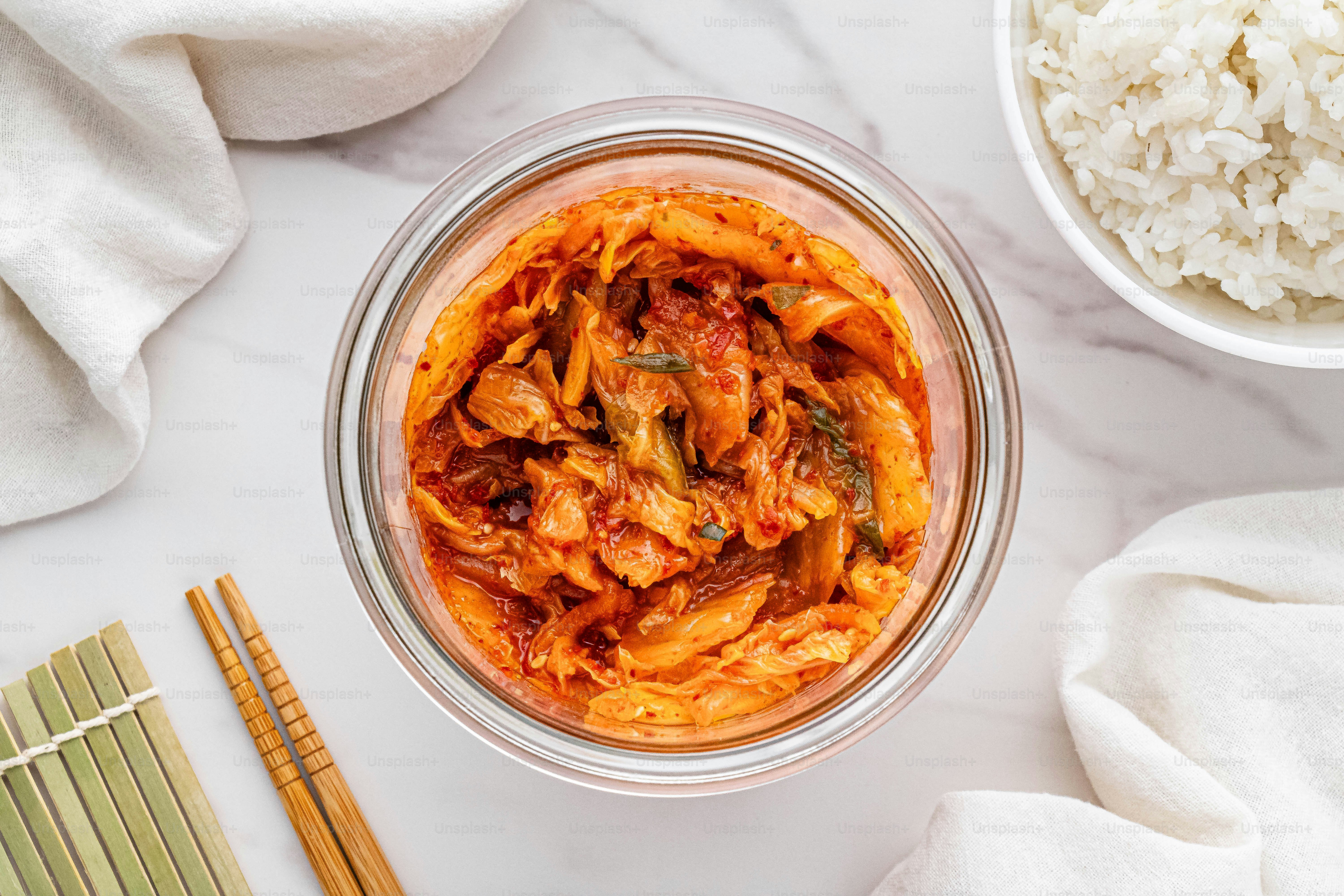 a glass bowl filled with food next to a bowl of rice