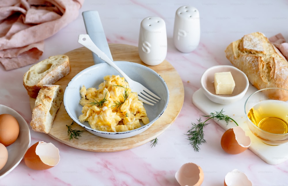 a bowl of eggs, bread, and butter on a table