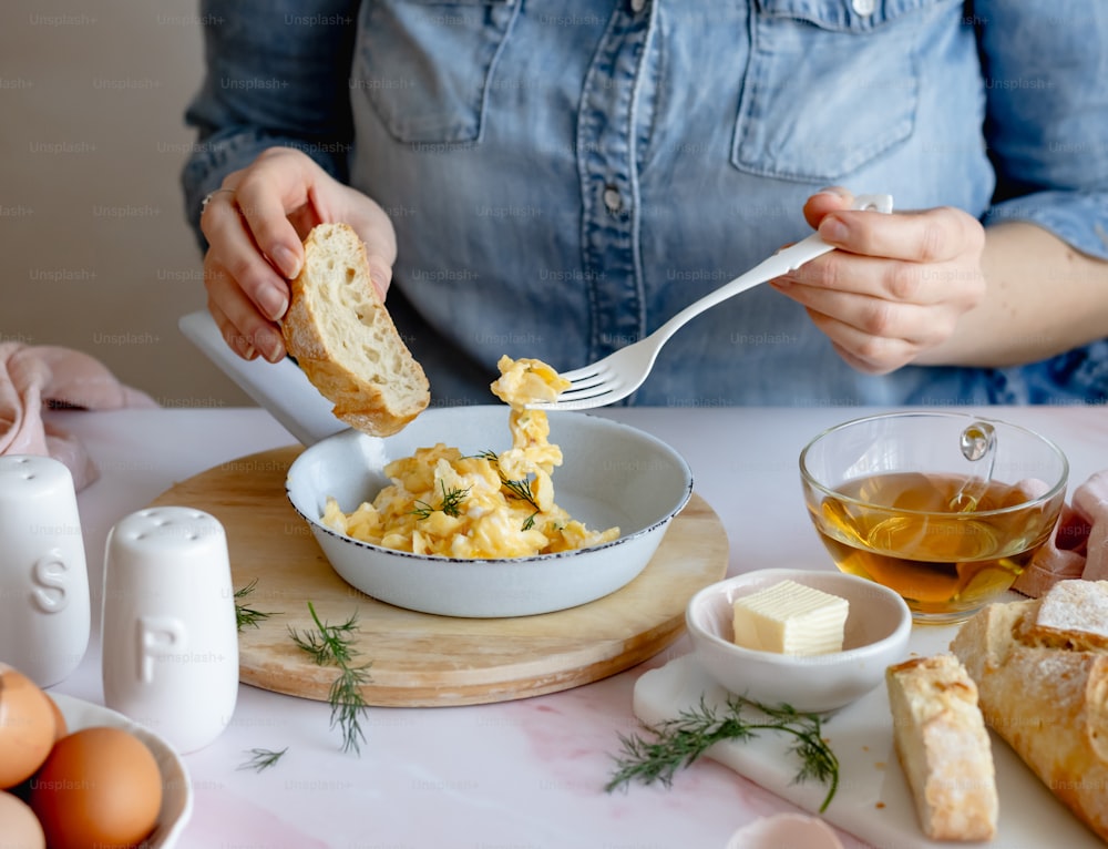 a woman is eating a bowl of scrambled eggs