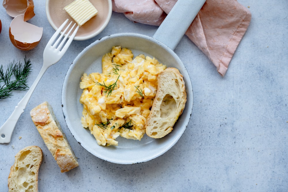 a bowl of scrambled eggs with bread and butter