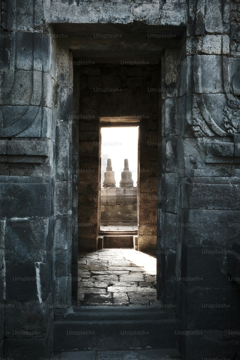 a doorway leading into a stone building with statues in the background