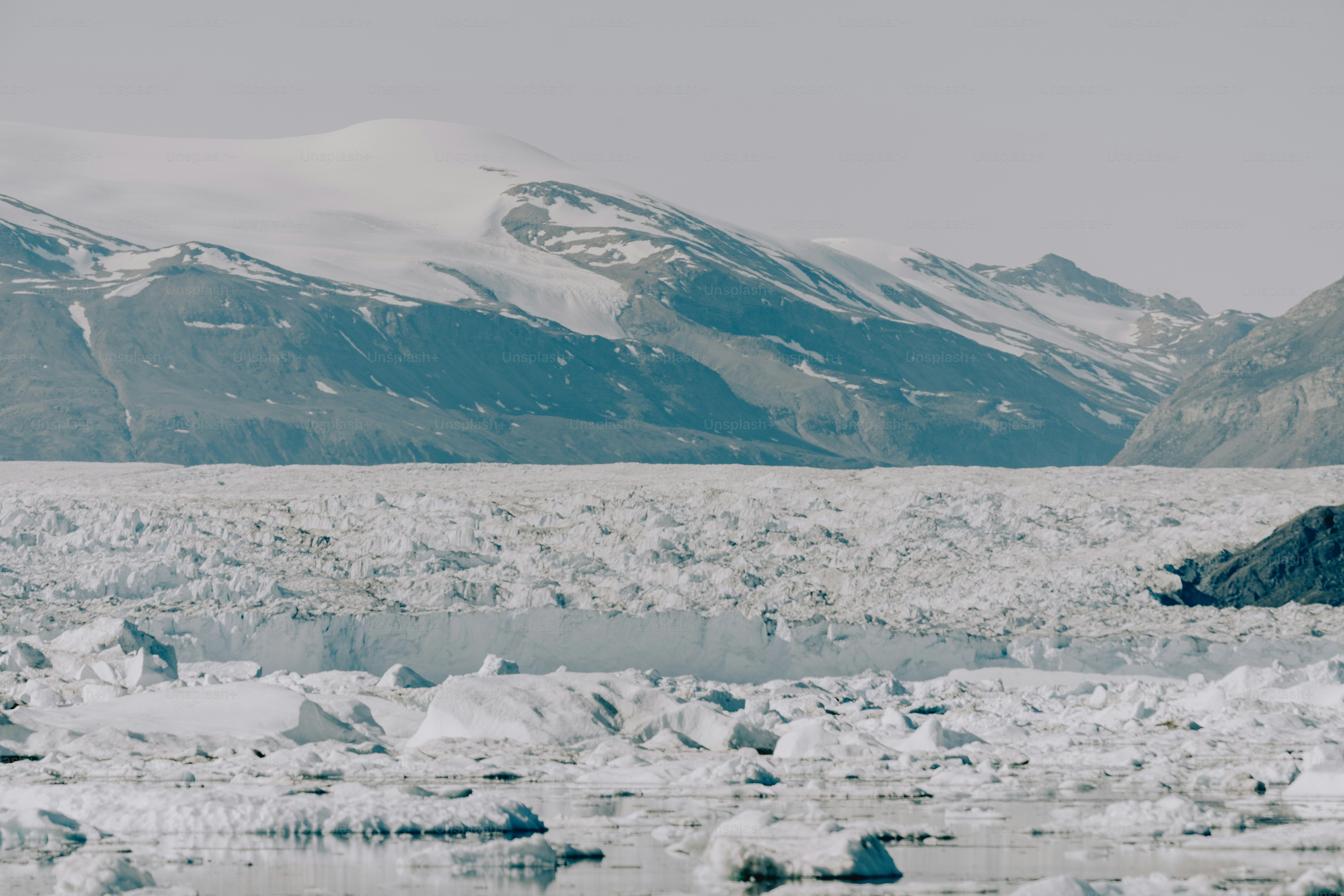 a large glacier with mountains in the background