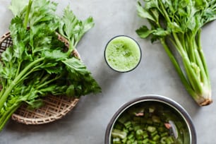 a bowl of celery next to a glass of green juice